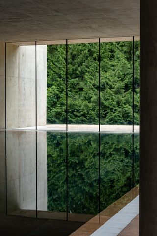 A linearly conceived spa features exposed cement and iron finishes and an infinity pool reflecting the outside's vegetation.