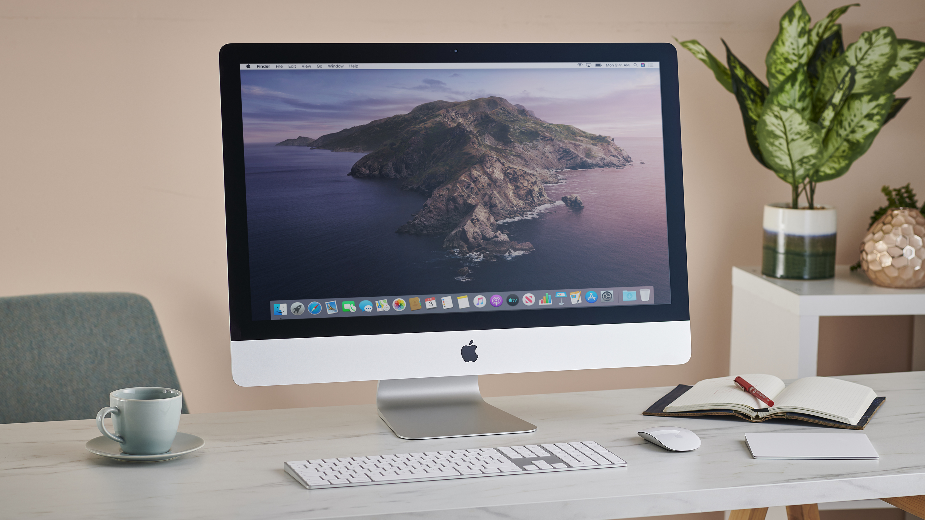 iMac 27-inch 2020 on home office desk, alongside notebook, coffee cup and houseplant