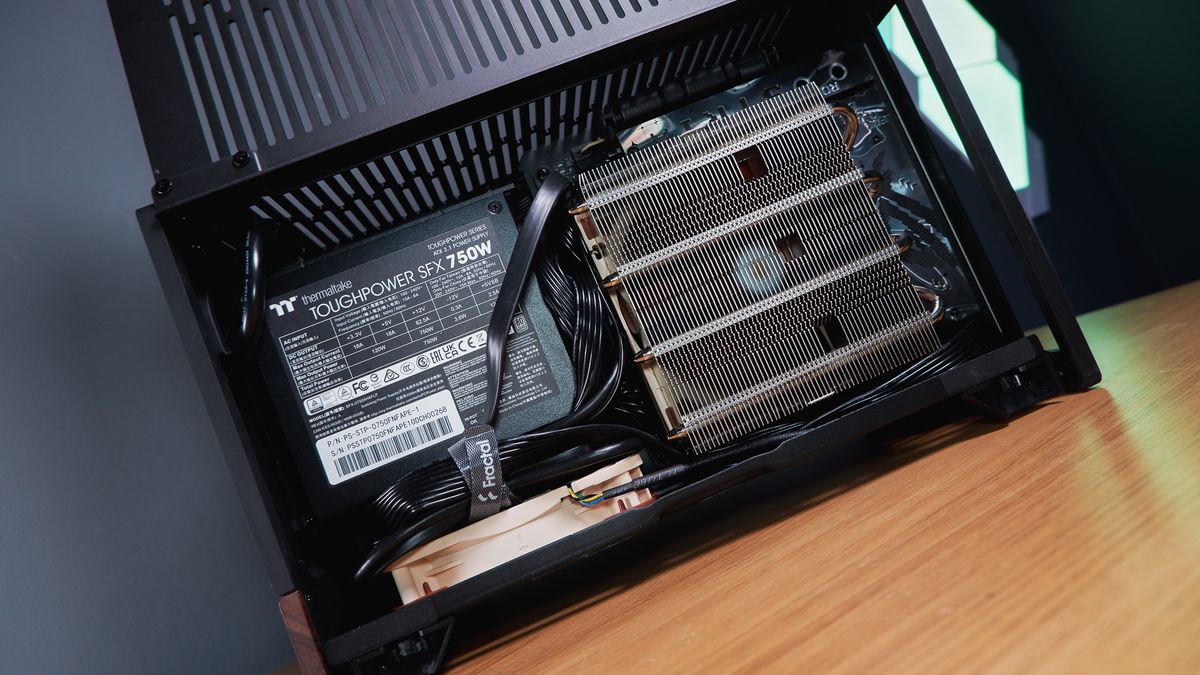 A compact gaming PC on a desk with various parts on show.