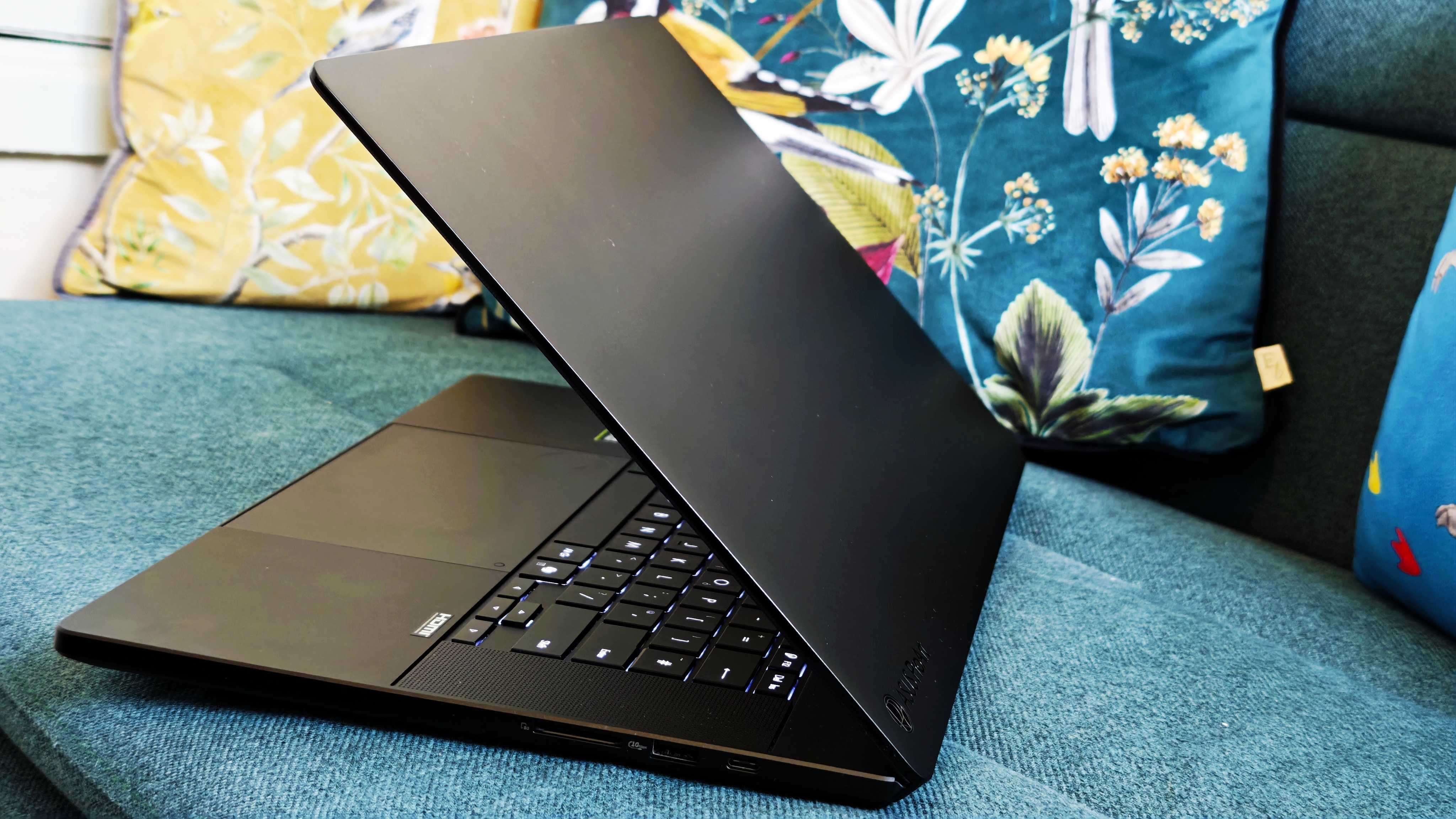 A black ASUS ProArt P16 laptop on a green sofa