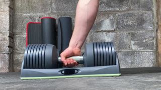 Image shows best adjustable dumbbell, JaxJox Connect, being used in a garage