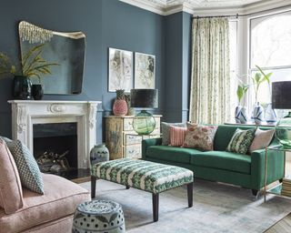 A green blue living room with a green sofa and pink armchairs