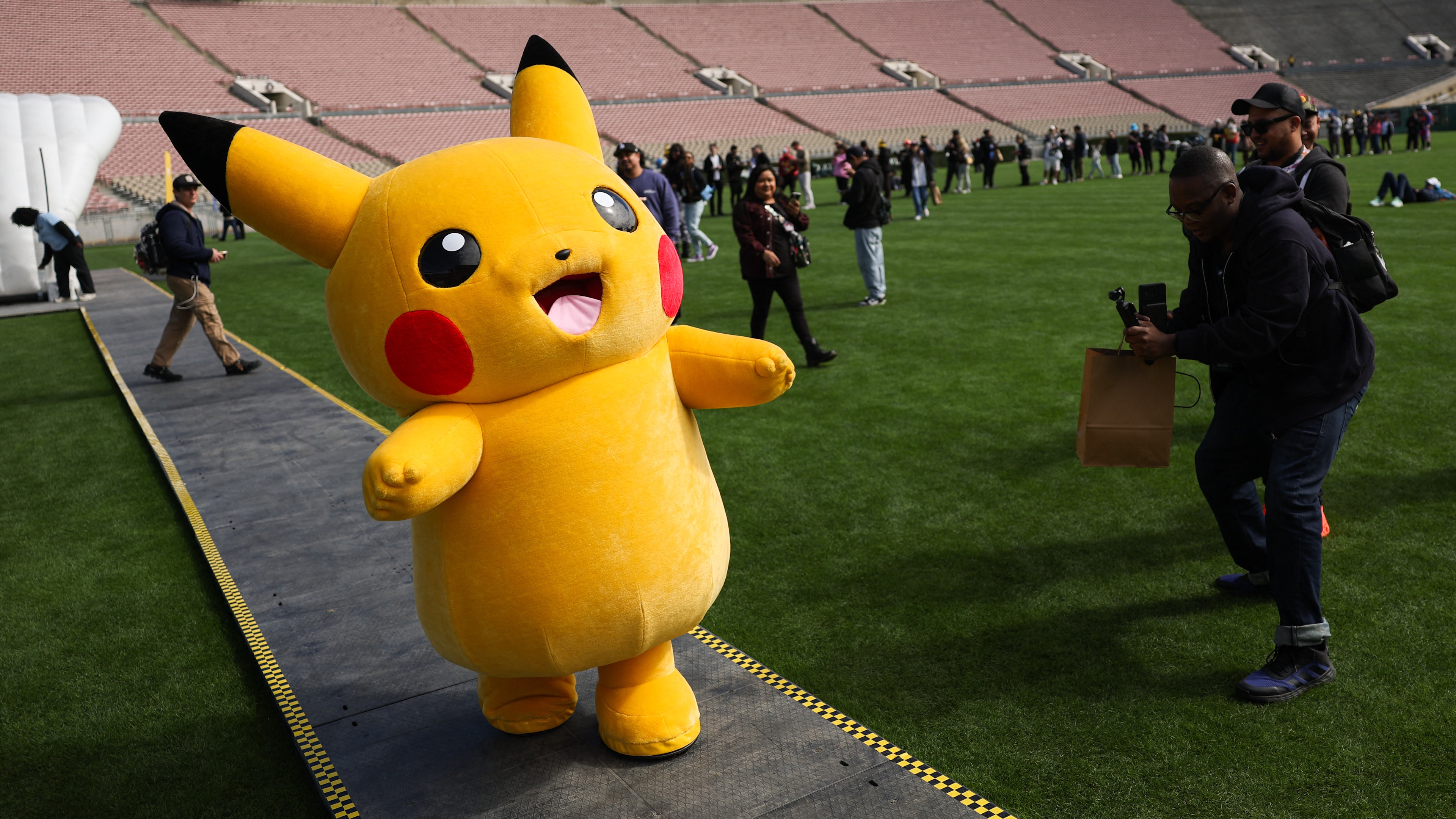 A Pikachu character walks across the field after posing for pictures with fans during the in-person Pokemon GO Tour: Kalos Los Angeles 2026 event at the Rose Bowl Stadium in Pasadena, California on February 20, 2026. Pokemon fans around the world continue to engage with the media franchise in various formats including video games, trading cards, animated series, and movies ahead of the 30th anniversary of Pok&eacute;mon next week. (Photo by Patrick T. Fallon / AFP via Getty Images)