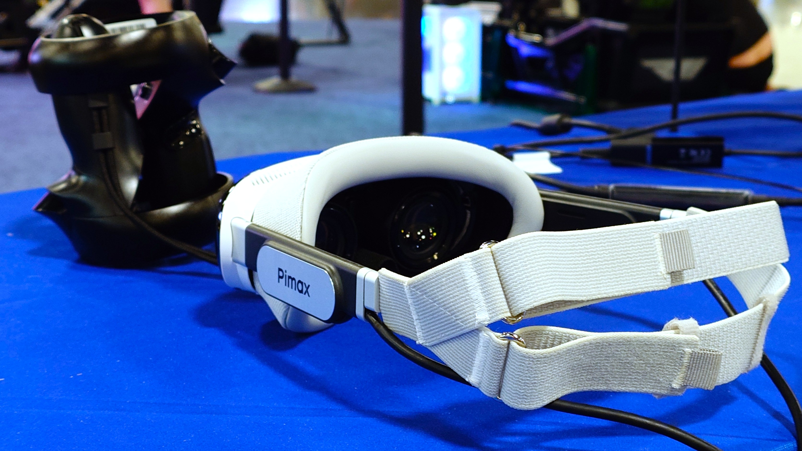 A photo of the Pimax Dream Air VR headset in white on a blue table with the hand controllers in front of it.