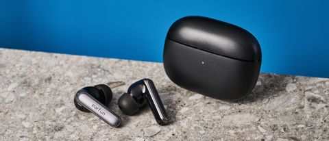 a pair of black and silver earbuds with silicone tips and a black charging case is photographed against a blue background