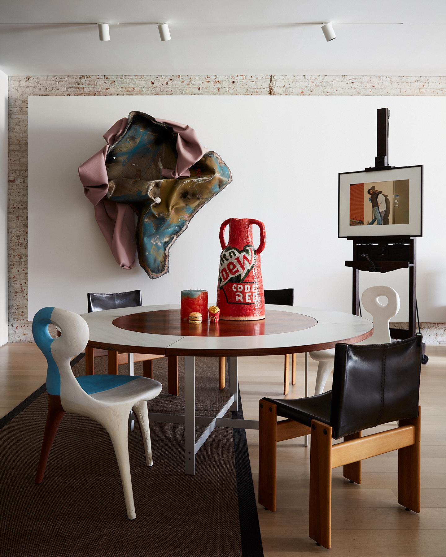 Dining table and sculptural chairs in apartment, with sculpture on wall