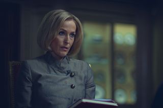 a woman (Gillian Anderson as Emily Maitlis), sitting down and holding a notebook, in the netflix movie 'scoop'