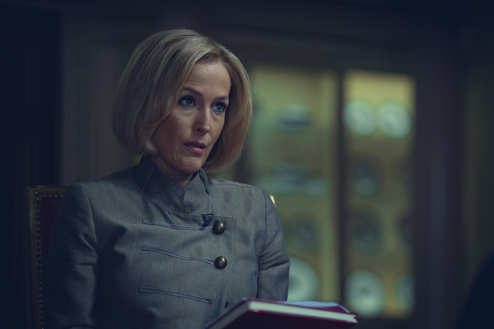 a woman (Gillian Anderson as Emily Maitlis), sitting down and holding a notebook, in the netflix movie 'scoop'