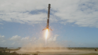 a white rocket lifts off under a sunny sky