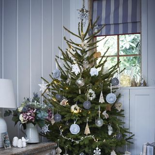 room with blue wall christmas tree and flowers in white vase