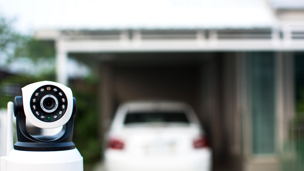 Best outdoor security cameras: Image depicts security camera in forefront of blurred car in driveway