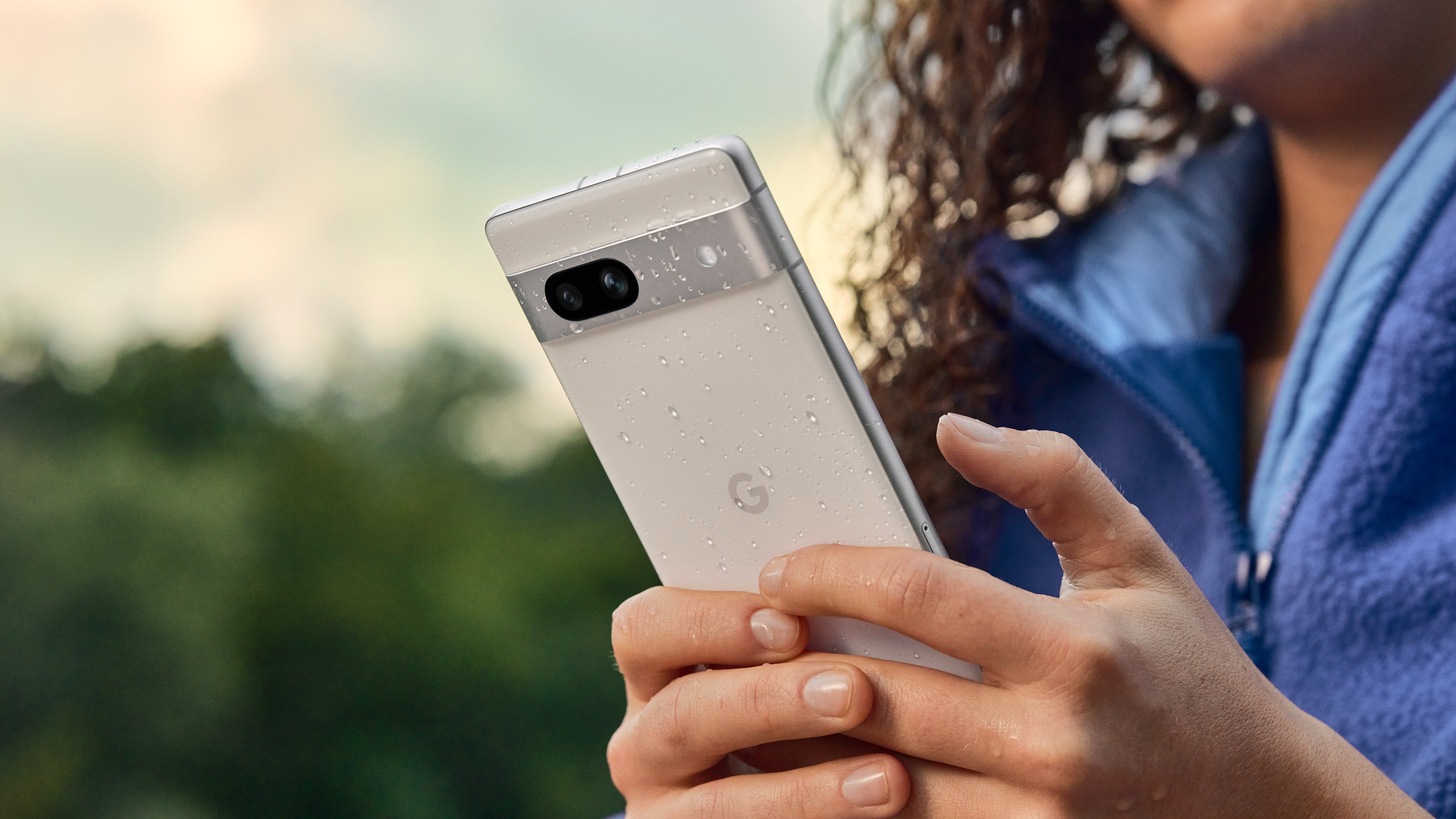 En person holder en hvit mobiltelefon av typen Google Pixel 7a.