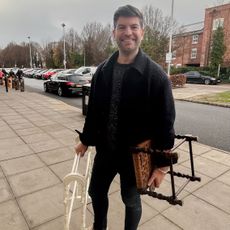 Man standing on street holding towel rail and stool
