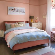 Coral bedroom with upholstered velvet bed and sheer curtains