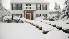 A white two-storey house and front garden covered in a thick layer of snow