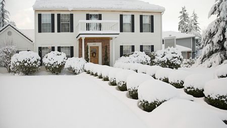 A white two-storey house and front garden covered in a thick layer of snow
