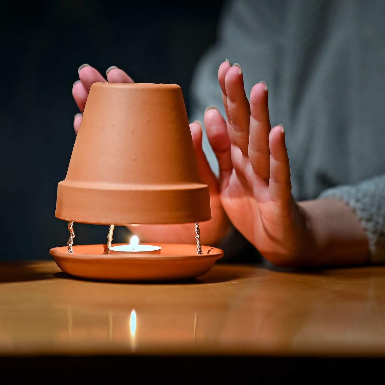 woman warming hands in front of clay pot heater