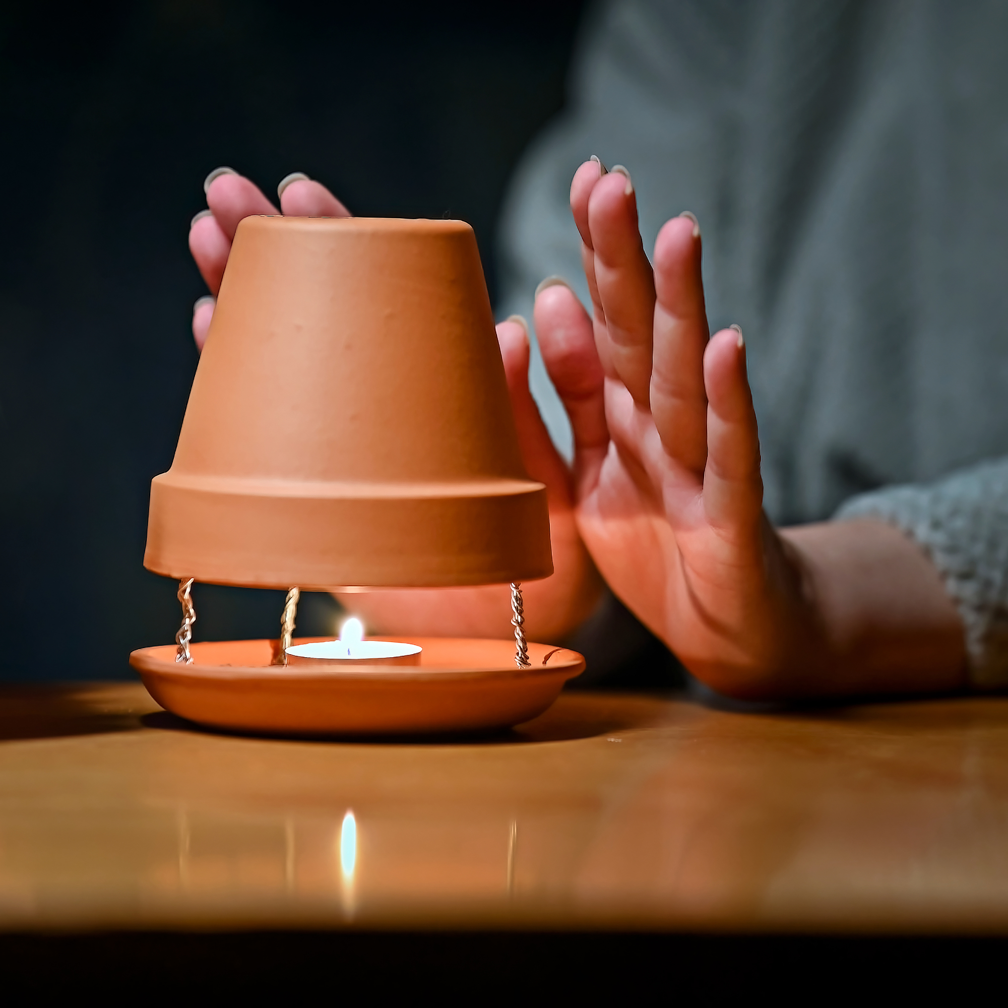woman warming hands in front of clay pot heater