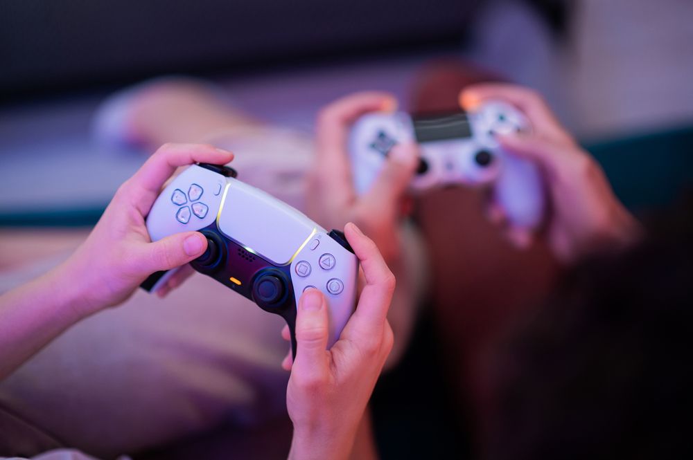 Children playing video games with a PS5 controller