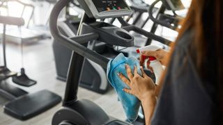 A woman cleaning a piece of gym equipment