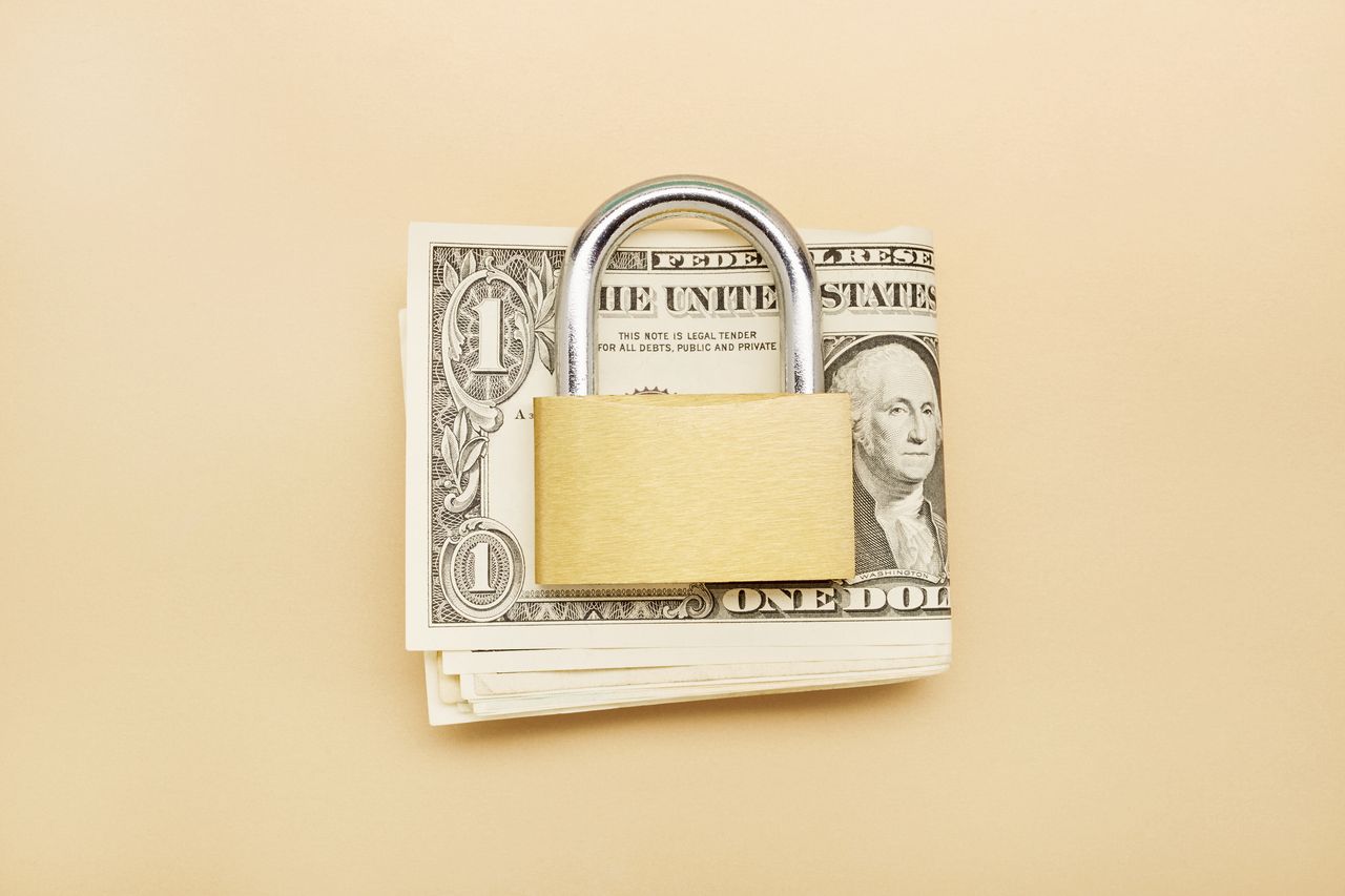 padlock on a stack of U.S. dollars