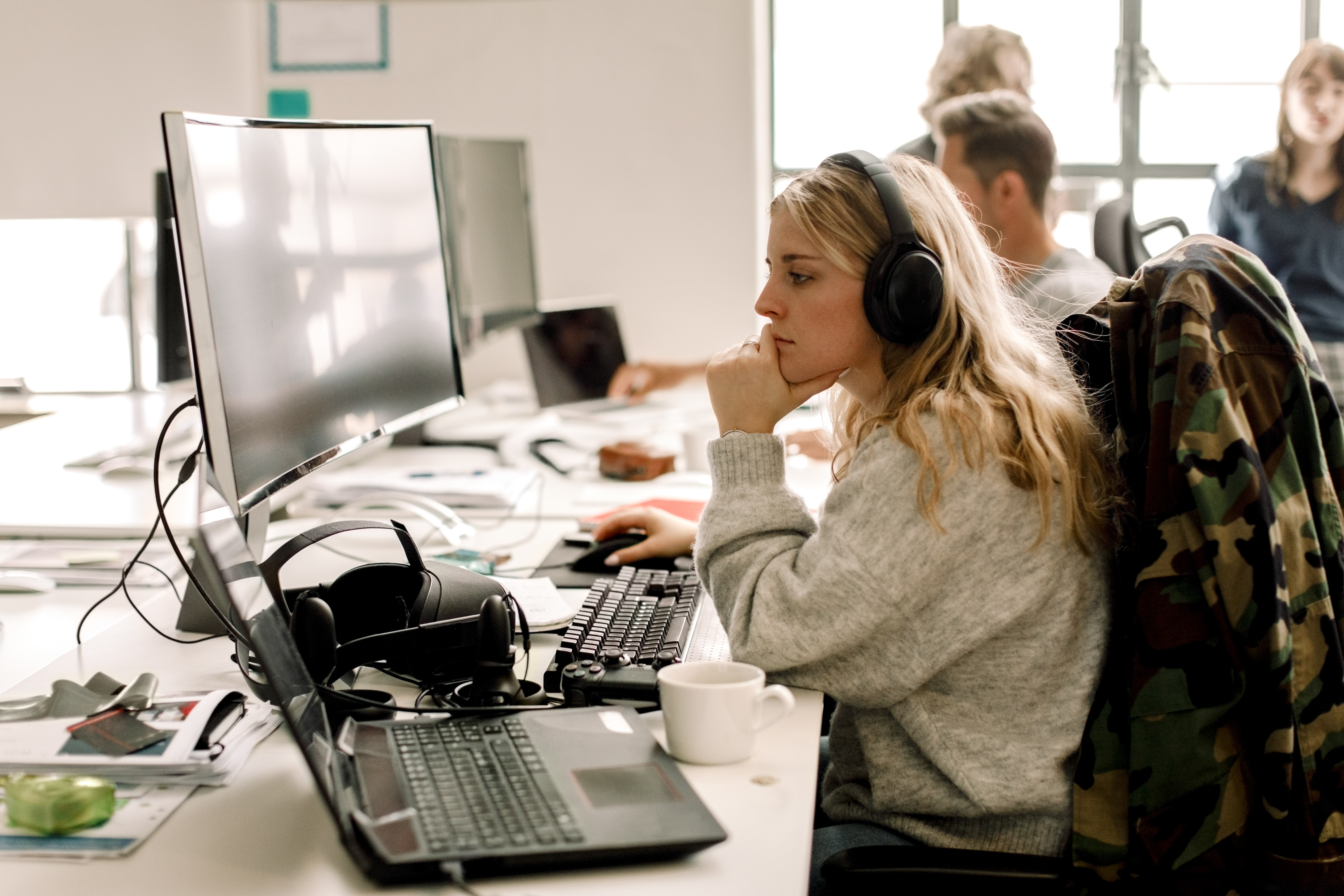 Young female software developer coding in Java programming language while sitting at a desk in an open plan office space.
