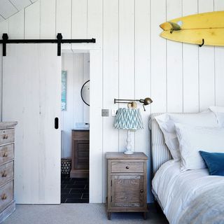 Bedroom with white panelled walls and sliding barn door to en suite