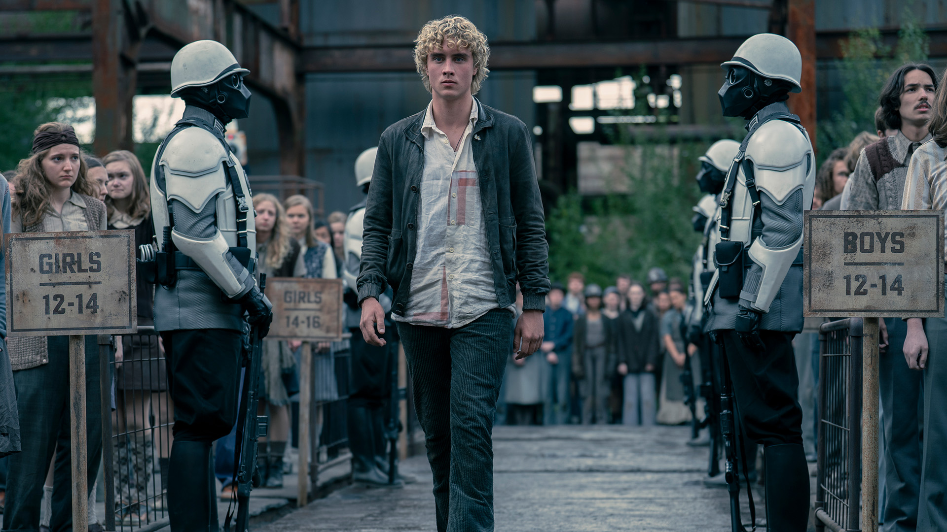 Joseph Zada as Haymitch Abernathy flanked by Peacekeepers.