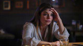 Lauren San Giacomo's Grace Confalone seated at bar with her left hand placed on her forehead in NCIS