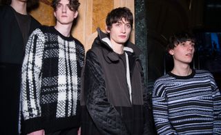 Three male models wearing looks from Pringle of Scotland's collection. One model is wearing a black and white check style jumper. Next to him is a model wearing a grey and black jacket with hood and a dark coloured top. And the third model is wearing a blue, white and black stripe patterned jumper