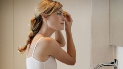 woman cleansing her face in front of sink