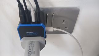 Ceptics 70W World Travel Plug Adapter plugged into socket with five USB leads and a UK plug attached