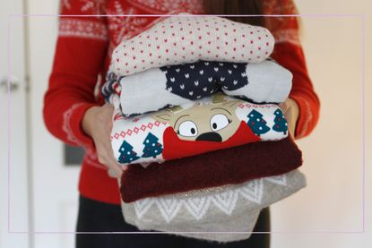 A woman holding a pile of Christmas jumpers
