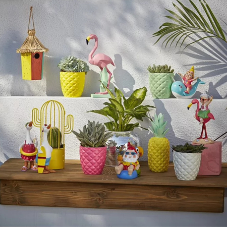 Silver disco ball planter on a bench with colourful pots and gnomes.