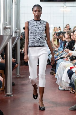 a runway model wears a tank top with white capri pants in Copenhagen