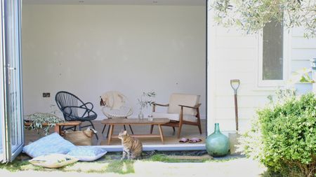 Sunny garden room with relaxed trio of seating, coffee table, and open door to garden.