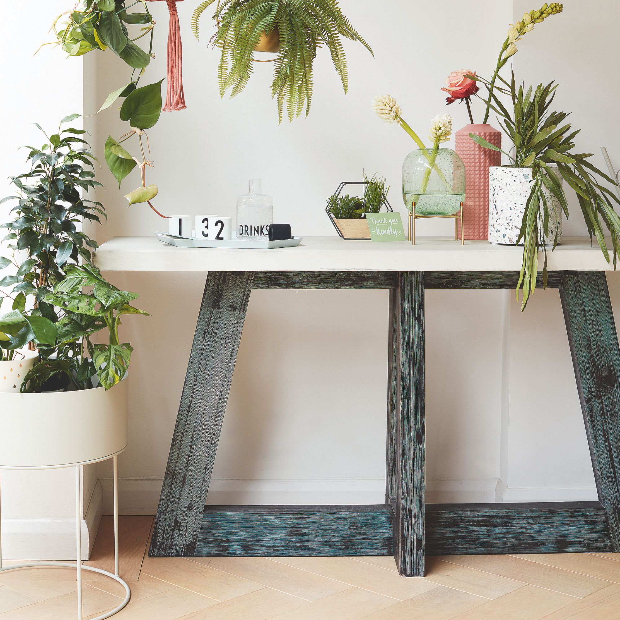 Room with wooden floors, and a table on top of it covered in houseplants