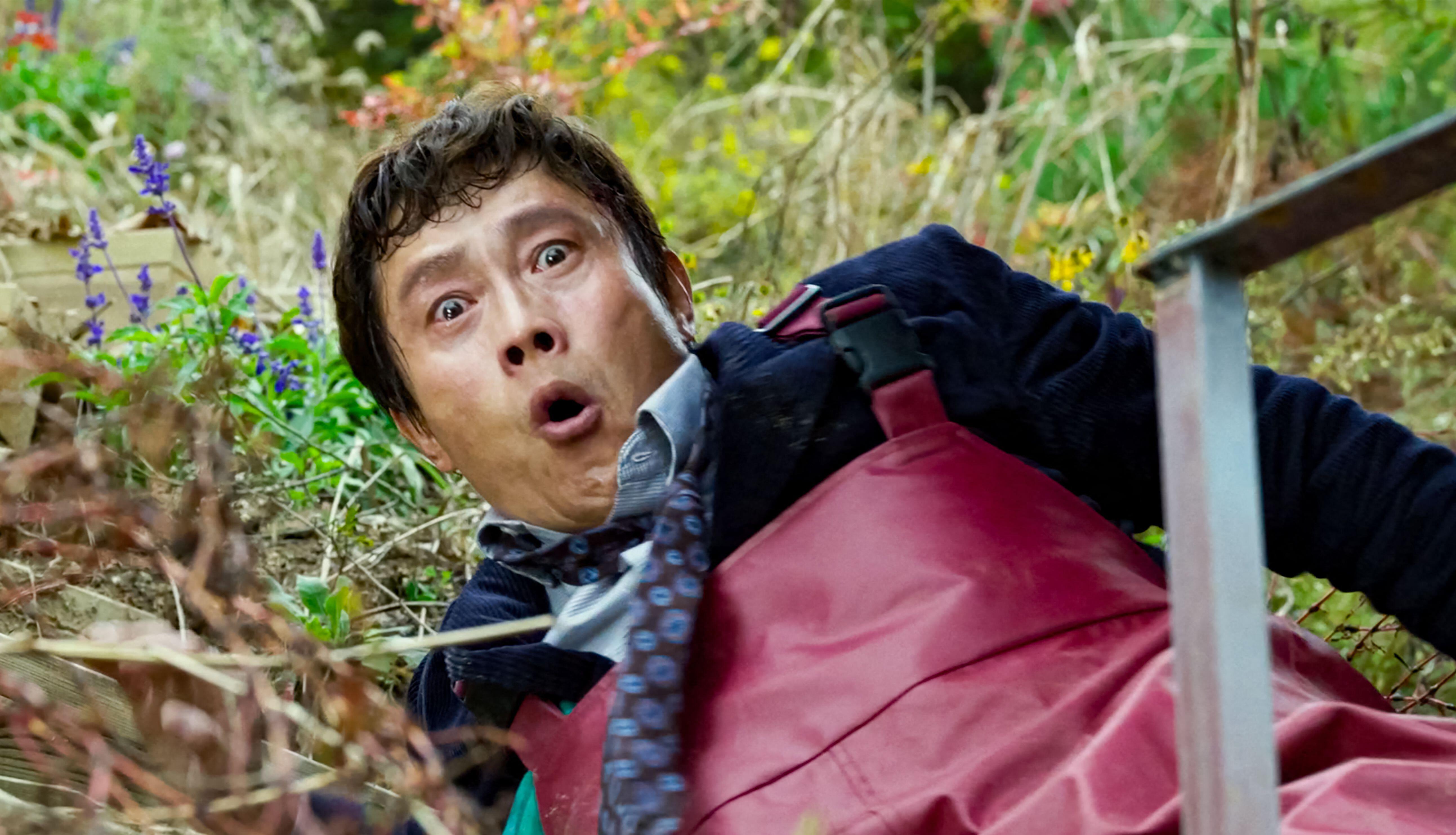 A shocked Man-su (Lee Byung-hun) lies in the grass in a scene from Park Chan-wook's "No Other Choice"