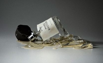 Bottle of byredo mixed emotions perfume smashed on the floor against grey background