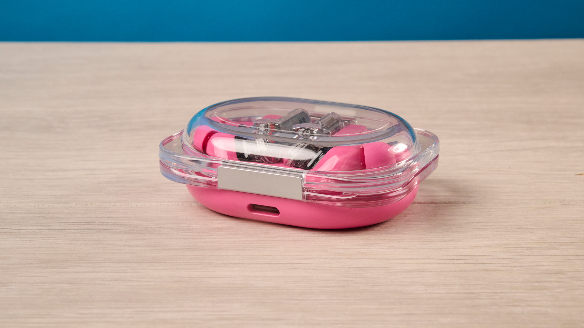The Nothing Earbuds (3a) in pink, on a wooden surface