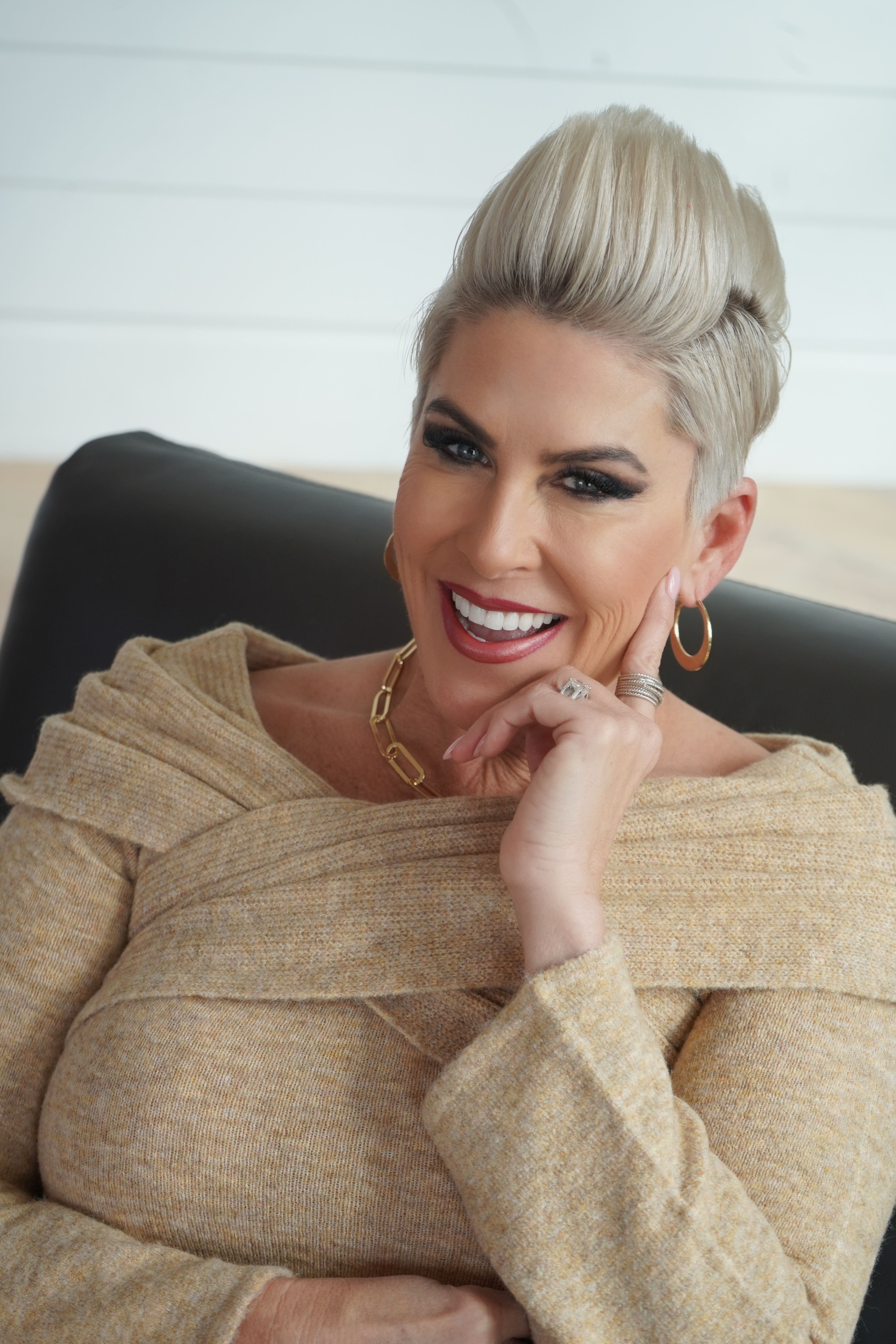 a professional headshot of a woman with blonde hair smiling while wearing a tan blouse
