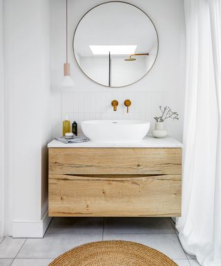 Small white bathroom with wooden floating vanity unit and large round mirror on wall