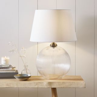 fluted glass table lamp with cream shade on wooden console table