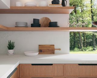 A kitchen with white quartz worktop, wooden shelves and assorted crockery on shelving