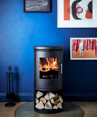 Morso 6143 freestanding fireplace on pedestal with dark blue wall decor and framed wall art