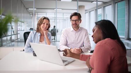 A couple smile as they work with an adviser on estate planning.
