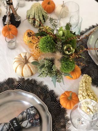 A Thanksgiving tablescape with mini pumpkins and a floral display