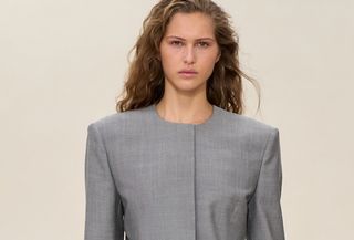 A model wearing a gray collarless blazer and matching skirt at the Calvin Klein F/W 25 show in New York.