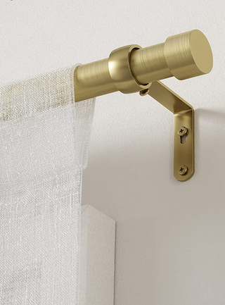gold curtain rod and holder holding up a sheer white curtain