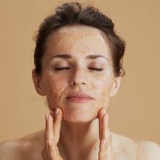 Woman with hair tied up massaging the best exfoliator into her skin